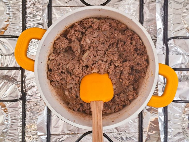 Carne triturada sendo incorporada à cebola refogada.