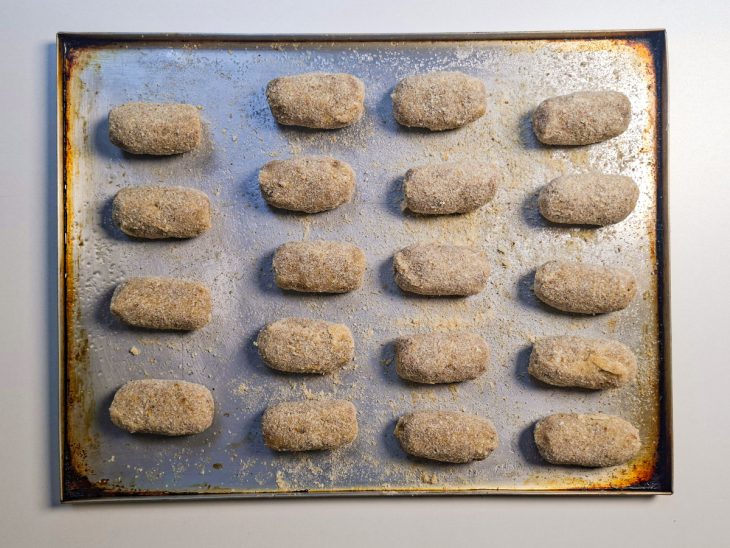 Croquetes sendo empanados novamente na farinha de rosca.