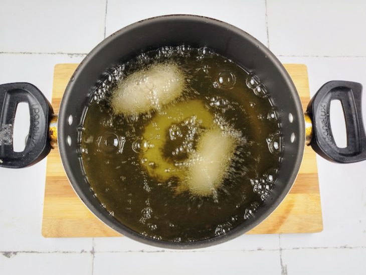 Croquetes fritando em óleo quente numa panela.