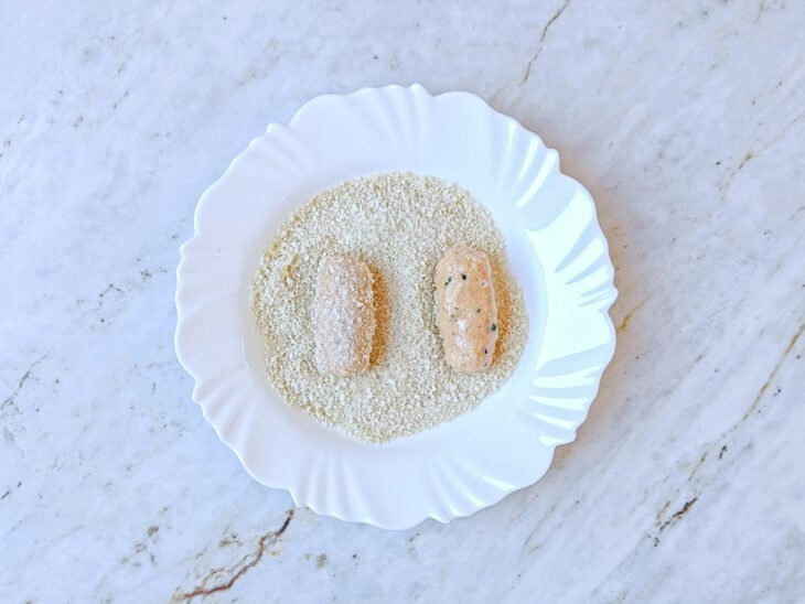 Croquetes sendo empanados na farinha panko.