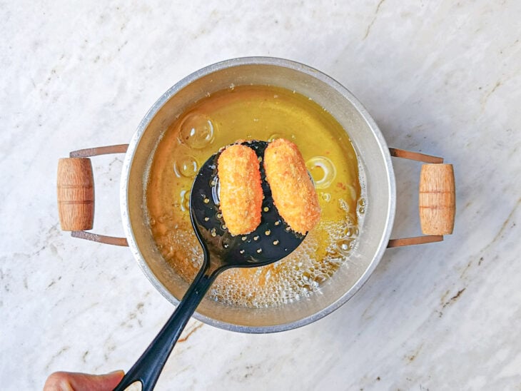 Croquetes dourados, saindo da panela com óleo.