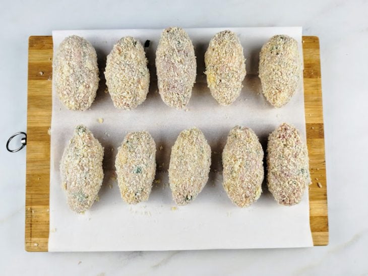 Croquetes empanados sobre uma tábua.