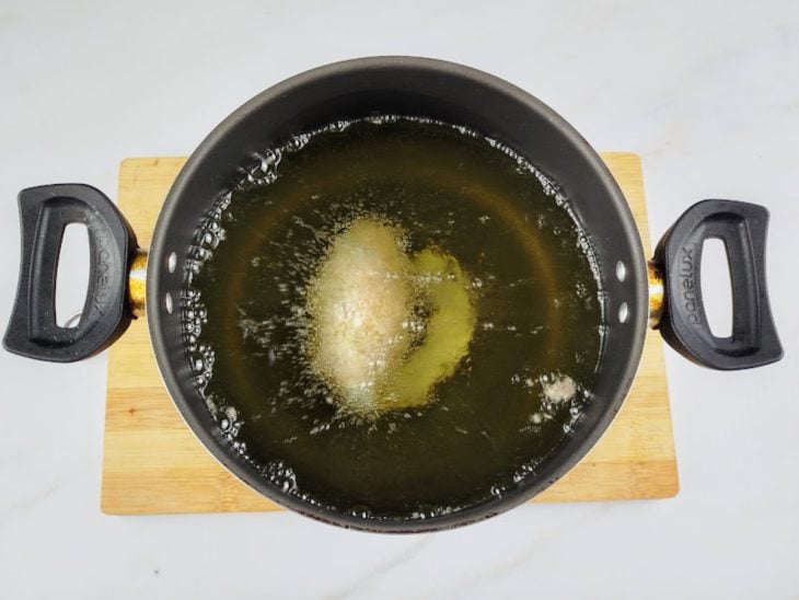 Uma panela com óleo e croquete a fritar.
