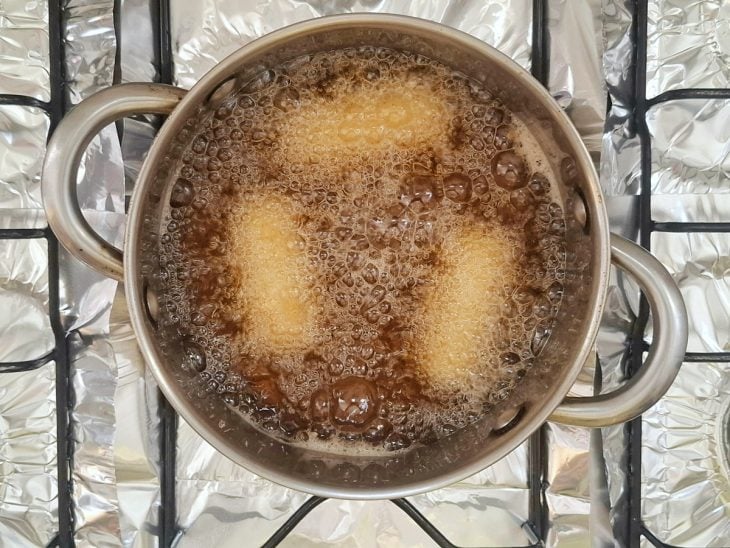 Croquetes fritando em óleo numa panela.