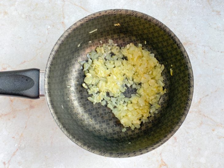 Uma panela com azeite, alho e cebola a dourar.