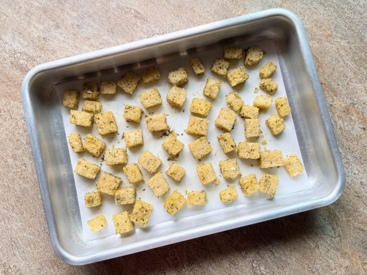 Cubos de pão dispostos numa assadeira.