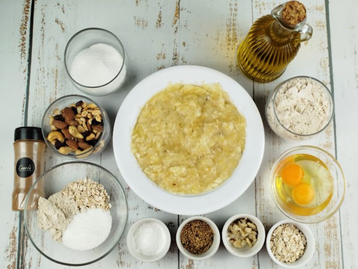 Bananas maduras amassadas em purê sobre a bancada com ingredientes organizados.