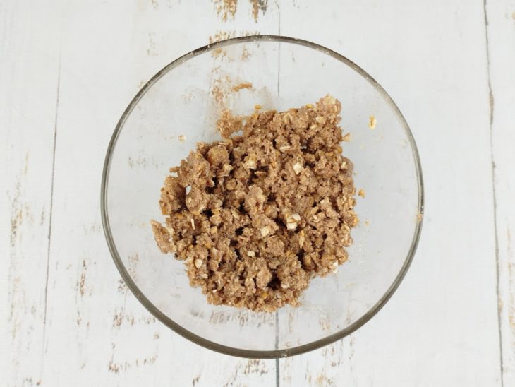 Farofa úmida sendo formada com óleo de coco misturado com as mãos.