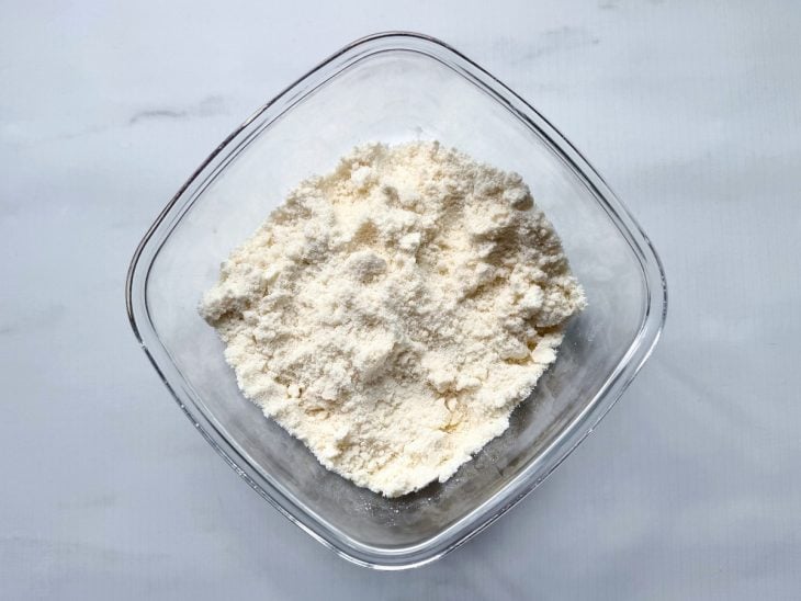 Farinha de trigo, manteiga e açúcar misturados na tigela.