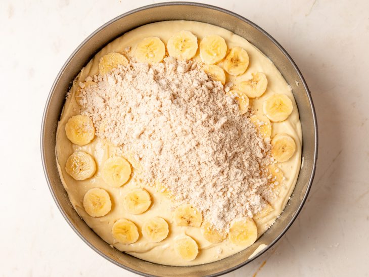 Farofa espalhada sobre a camada de rodelas de banana na forma.
