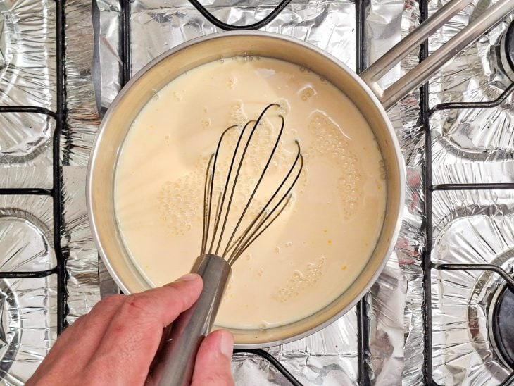 Creme sendo preparado na panela com mistura sendo mexida até engrossar.
