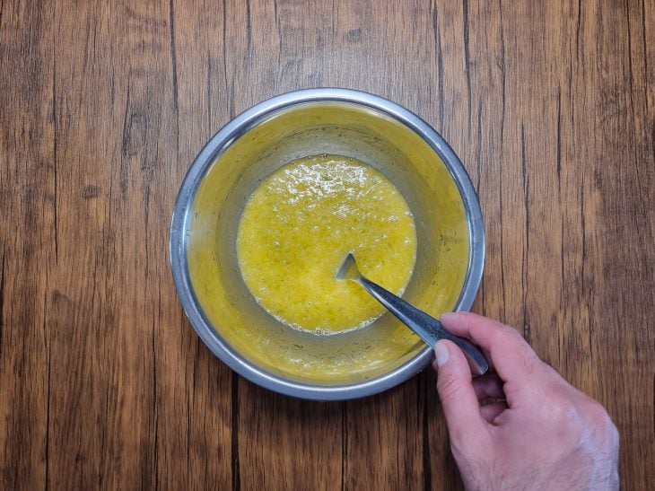 ovos, raspas, suco das laranjas, açúcar, manteiga, pinga e sal misturados em uma tigela