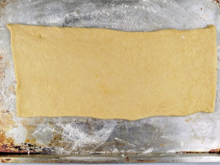 Massa aberta sobre a superfície untada com farinha.