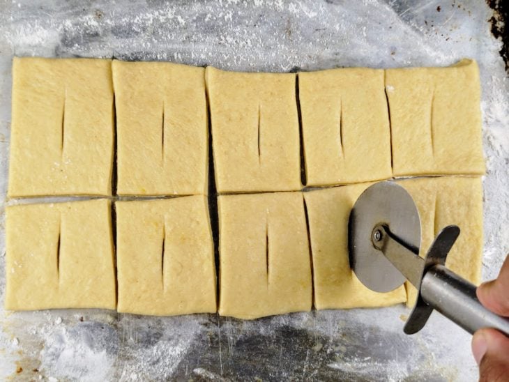 Massa cortada com auxílio de um cortador de pizza.
