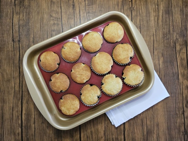 Uma forma com várias forminhas com cupcakes assados.