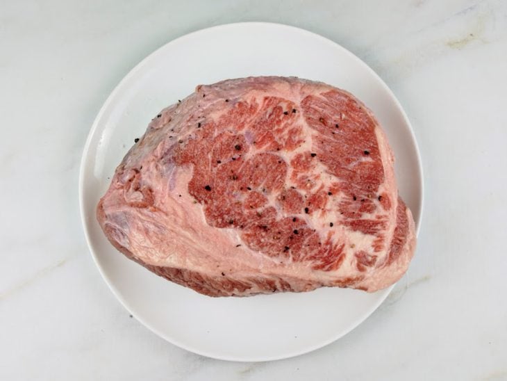 Peça de carne temperada com sal e pimenta-do-reino.