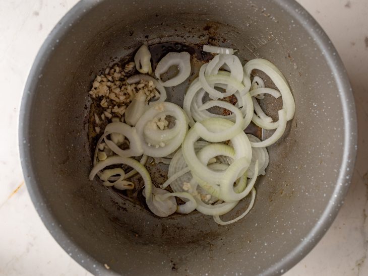 Alho e cebola refogando na panela de pressão.