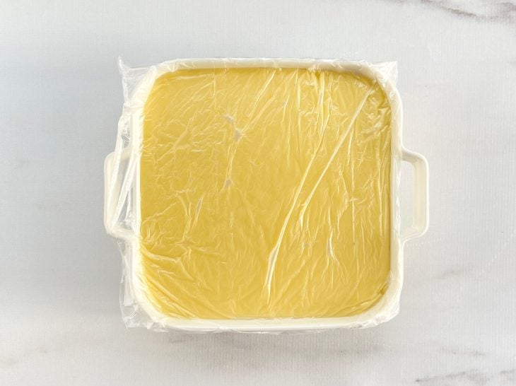 Um recipiente contendo curau de milho verde, coberto com plástico filme.