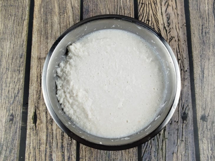 Leite integral morno sendo despejado sobre os ingredientes misturados na tigela.