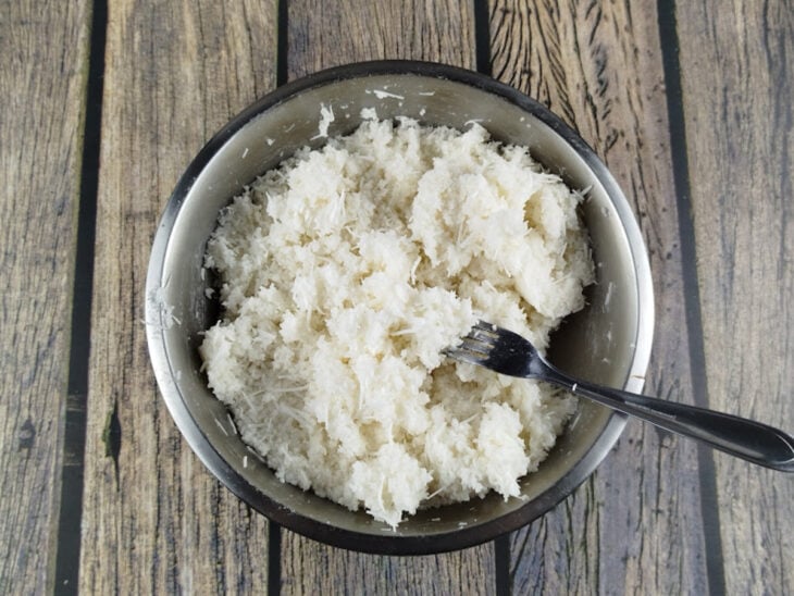 Massa de tapioca úmida sendo solta com um garfo até atingir textura de farofa.