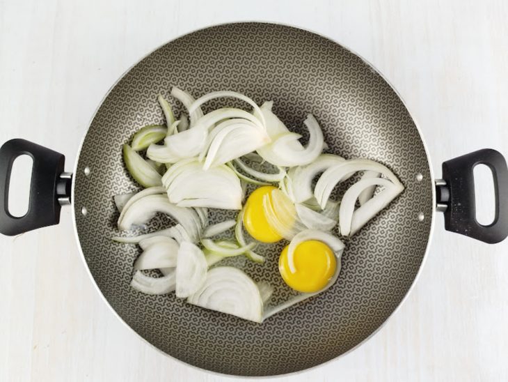Ovos e cebola sendo refogados em fogo médio com óleo.