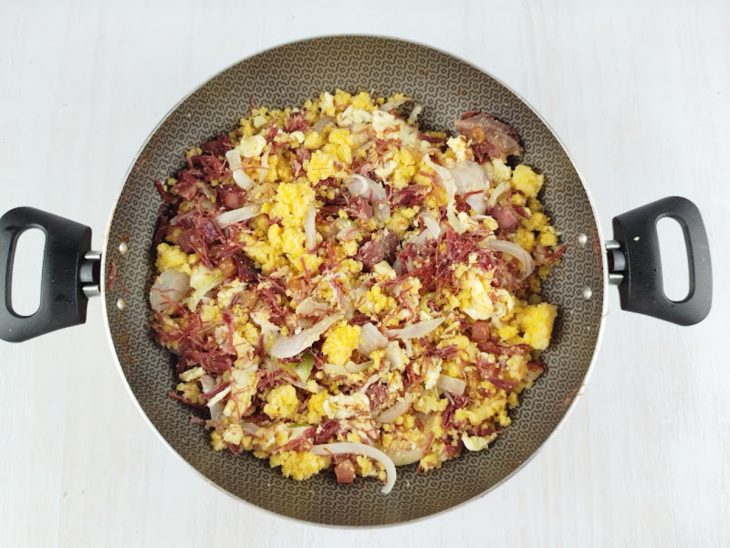 Cuscuz sendo incorporado à carne, junto com manteiga e ovos mexidos.