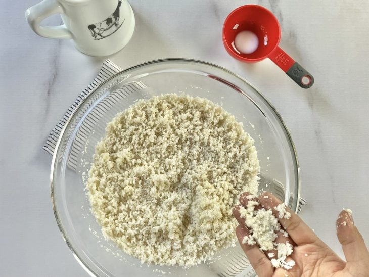 Uma tigela contendo leite, flocão de arroz, açúcar, sal, manteiga, óleo e coco ralado.