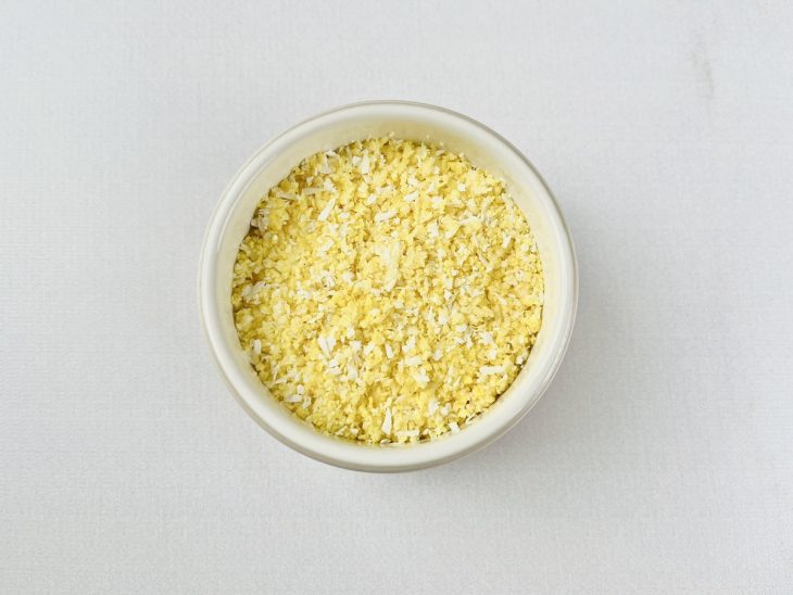 Massa do cuscuz acomodada no recipiente untado.