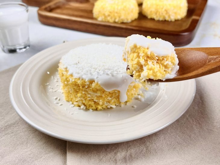 Cuscuz doce servido num prato individual e finalizado com leite de coco e coco ralado.