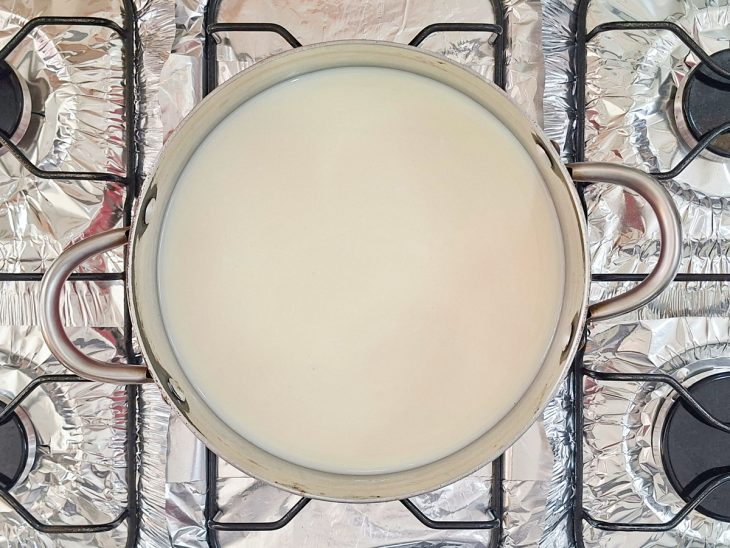 Leite, leite condensado e o açúcar misturados na panela.