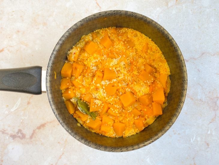 Panela com o cuscuz, vegetais, temperos e água para hidratar.