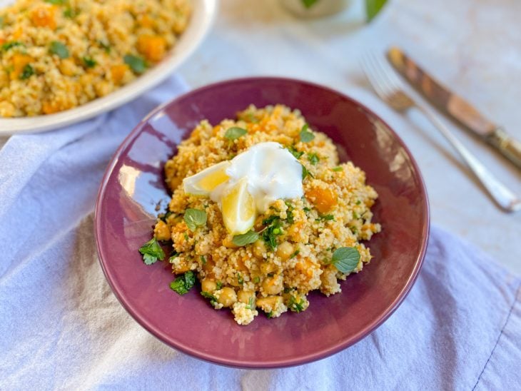 Um prato contendo cuscuz marroquino com legumes servido com iogurte.