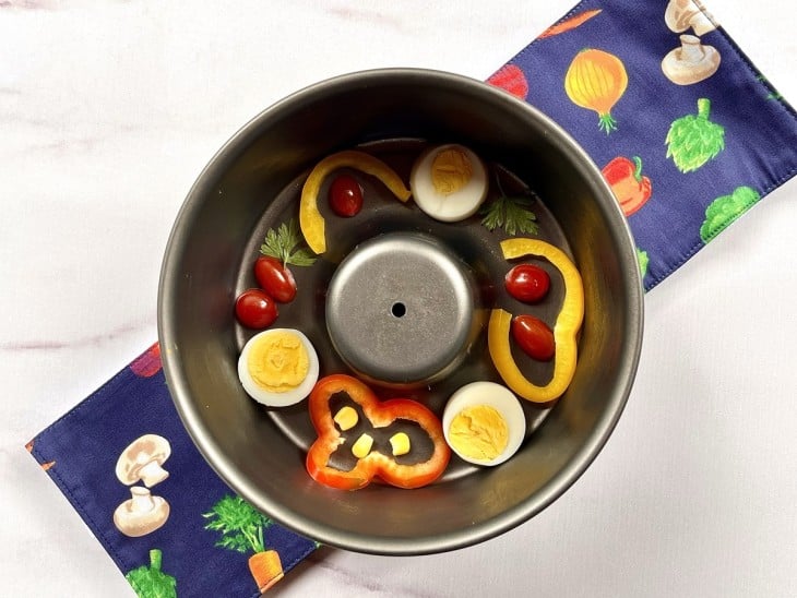 Uma forma decorada com tomates, ovos, fatias de pimentão e milho.