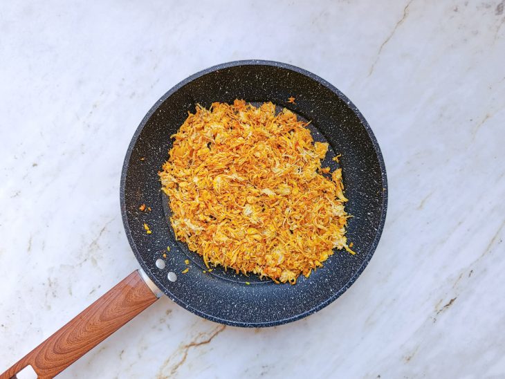 Frango desfiado sendo misturado ao refogado.