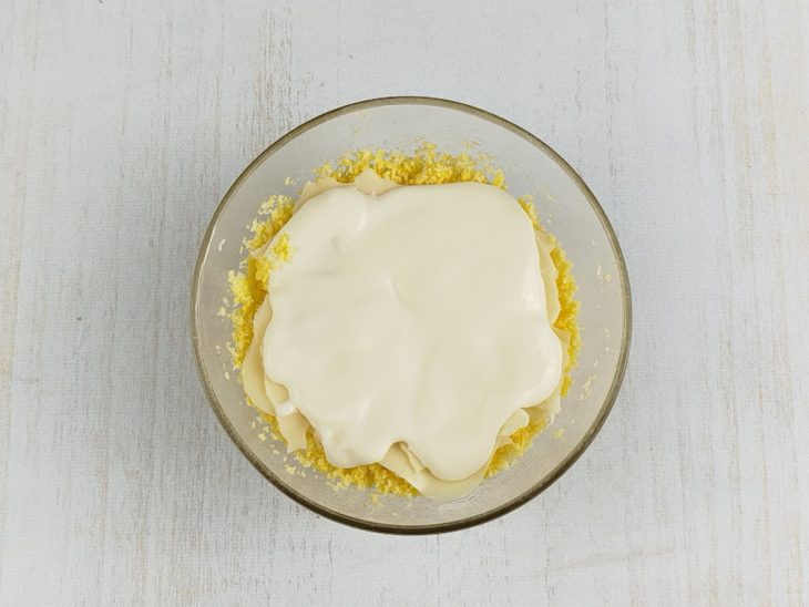 Queijo e requeijão acomodados sobre a massa misturada.