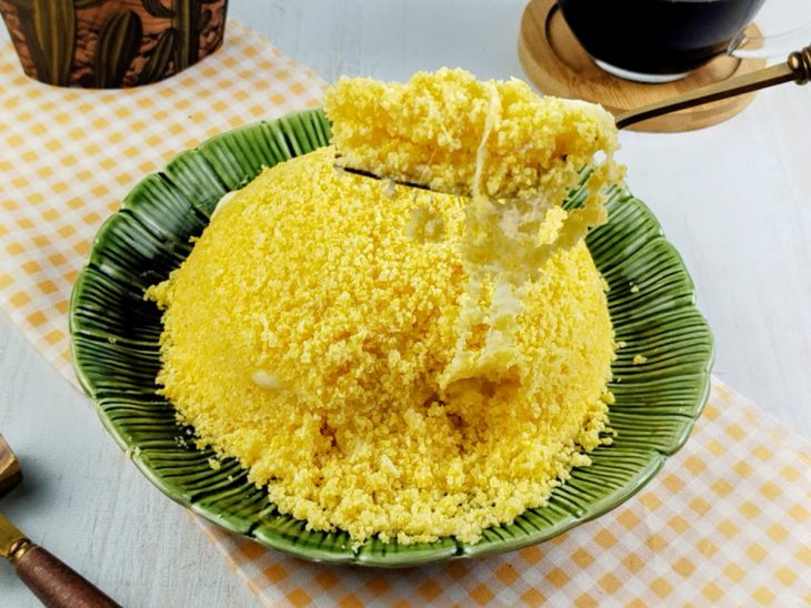 Cuscuz desenformado num prato com porção em destaque num garfo.