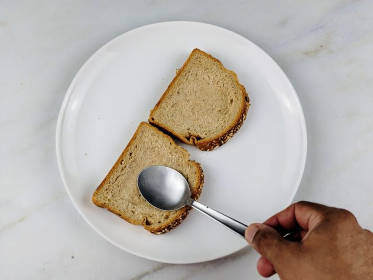 Fatias de pão sendo pressionadas por uma colher.