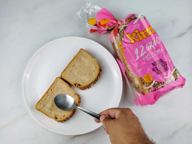 Fatias de pão sendo pressionadas com uma colher para formar uma cavidade.
