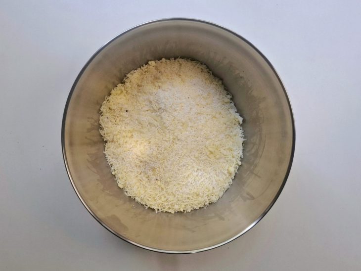 Uma tigela com tapioca, queijo ralado, sal e pimenta-do-reino.