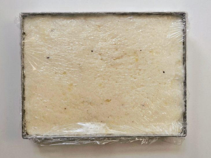 Uma forma com a massa do dadinho coberta com plástico-filme.