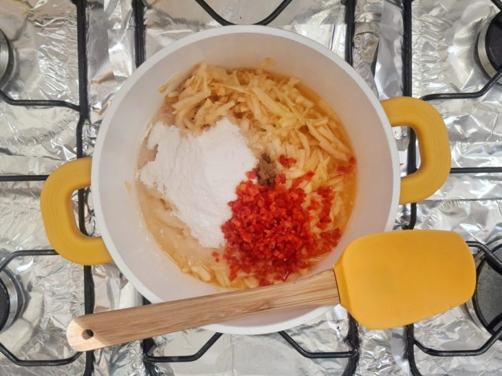 Uma panela com pimenta, maçã, suco do limão, açúcar, sal, canela em pó e água.