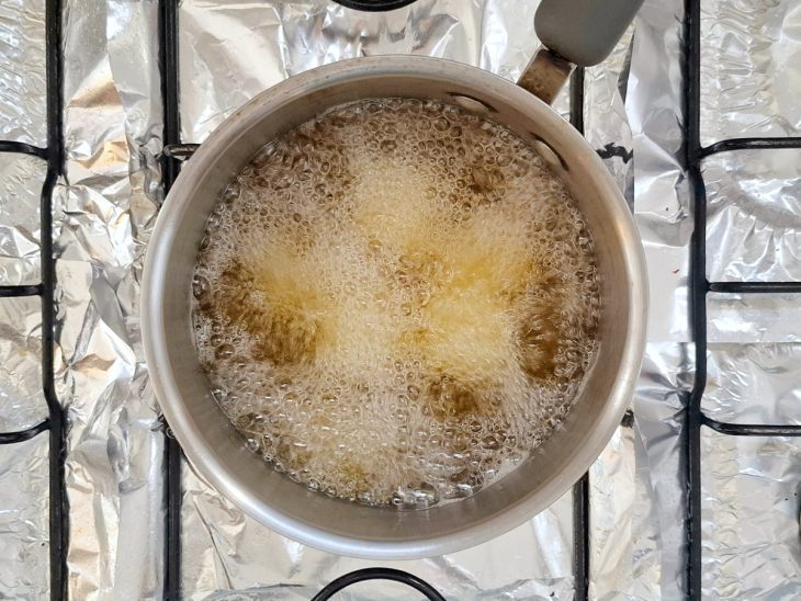 Uma panela com óleo e dadinhos fritando.