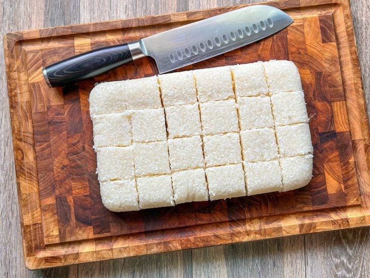 Massa de tapioca cortada em cubinhos sobre uma tábua de cozinha.