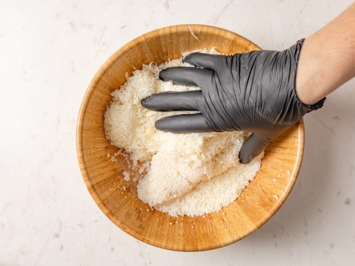 Queijo coalho ralado adicionado à mistura de tapioca com leite na tigela.