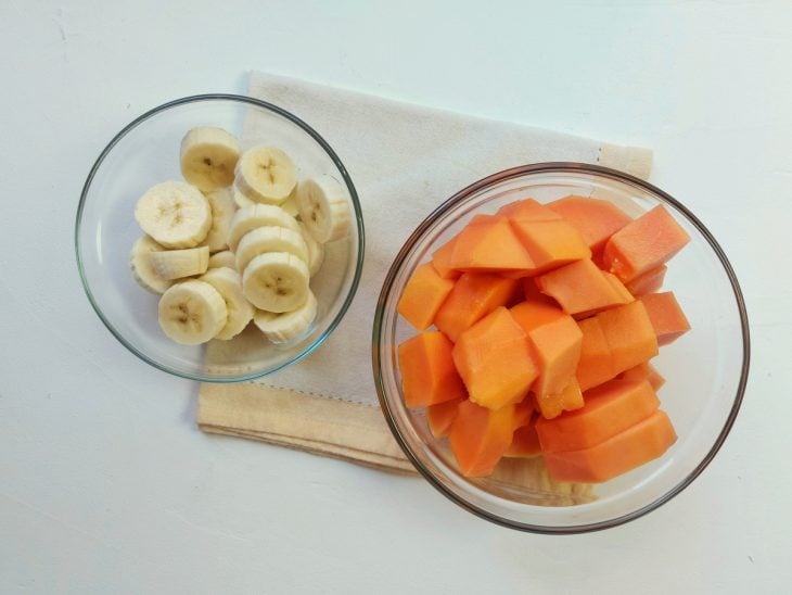 Recipiente contendo mamão e bananas picadas.