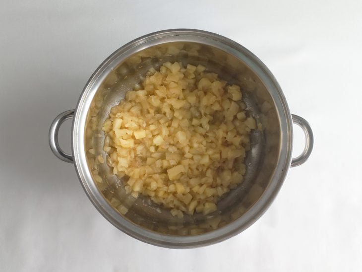 Suco de abacaxi, açúcar refinado e pedaços de abacaxi numa panela.