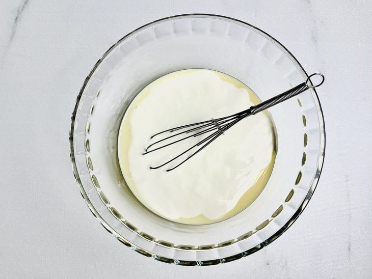 Leite condensado e creme de leite em uma tigela de vidro.