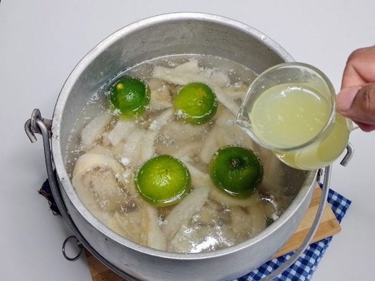 Uma panela contendo bucho, água, caldo de limão e limões.