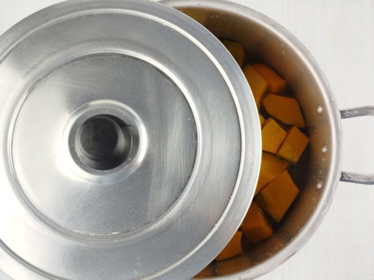 Panela tampada pela metade, com a abóbora dentro.