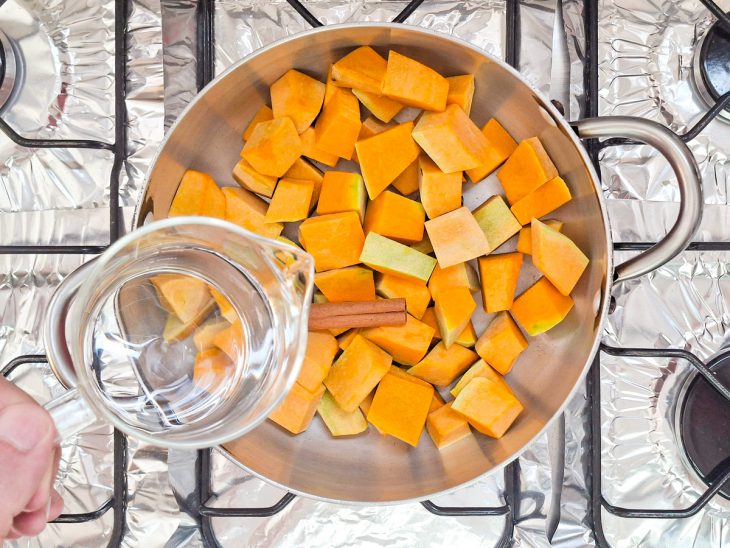 Abóbora, canela em pau e água na panela antes de iniciar o cozimento.